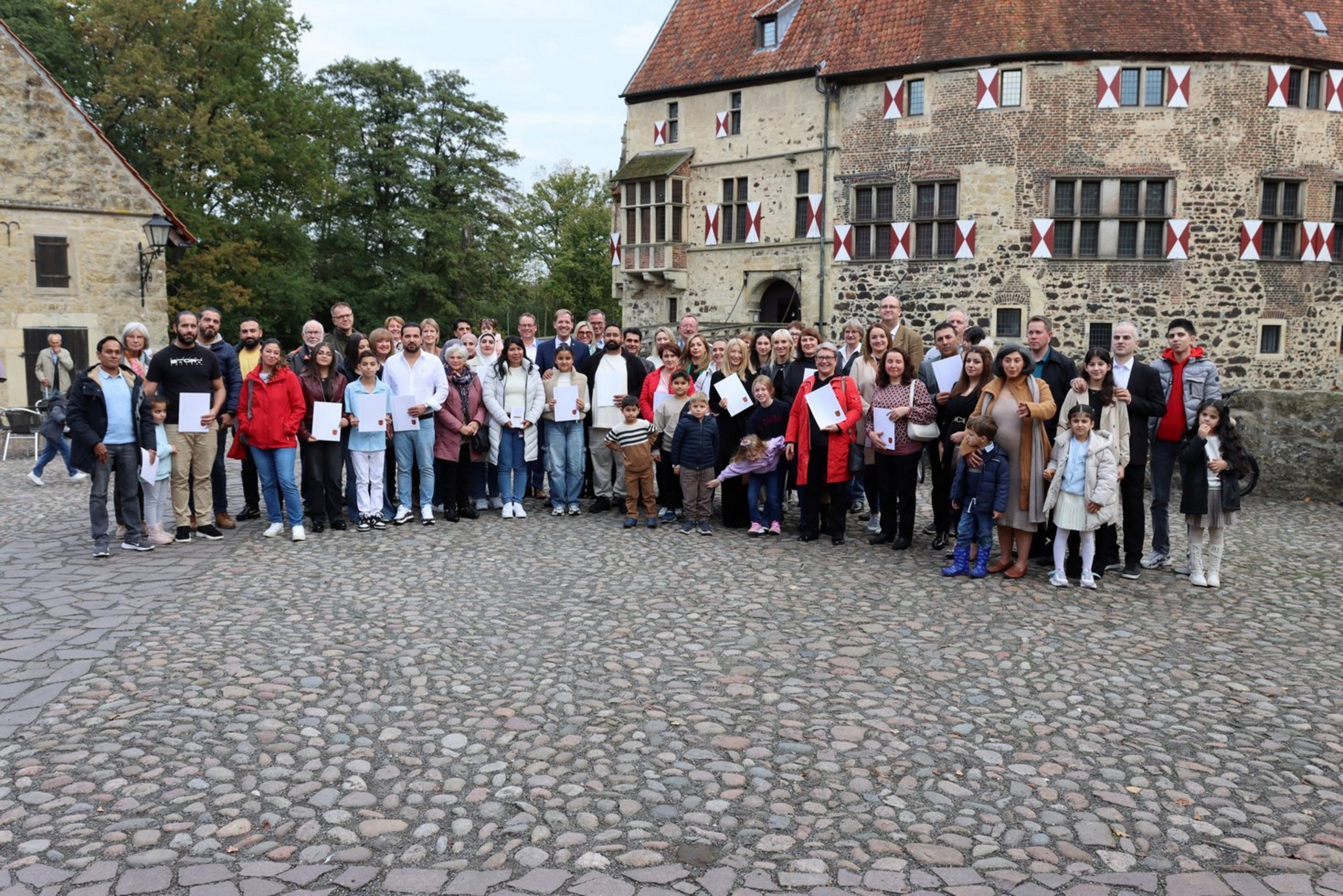 Eine große Gruppe von Menschen steht zur Einbürgerungsfeier vor der Burg Vischering in Lüdinghausen.