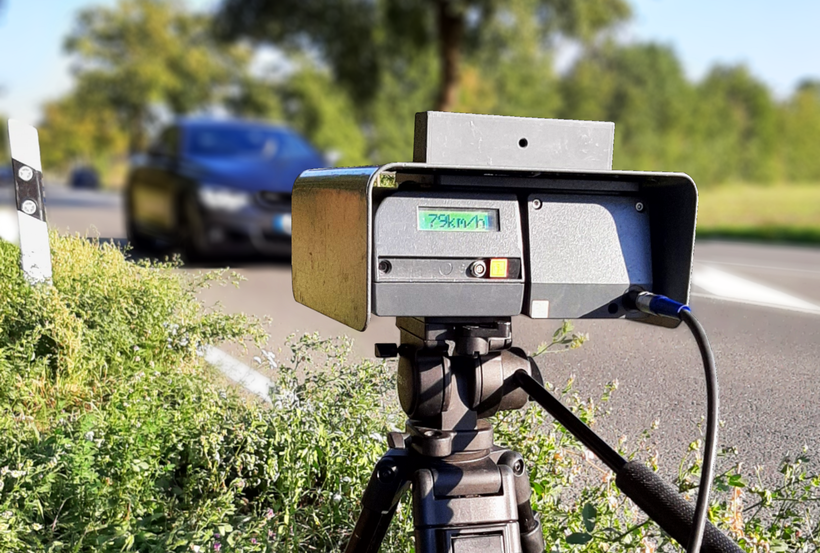 Ein Tempomessgerät steht am Straßenrand und ist auf ein heranfahrendes Auto ausgerichtet.