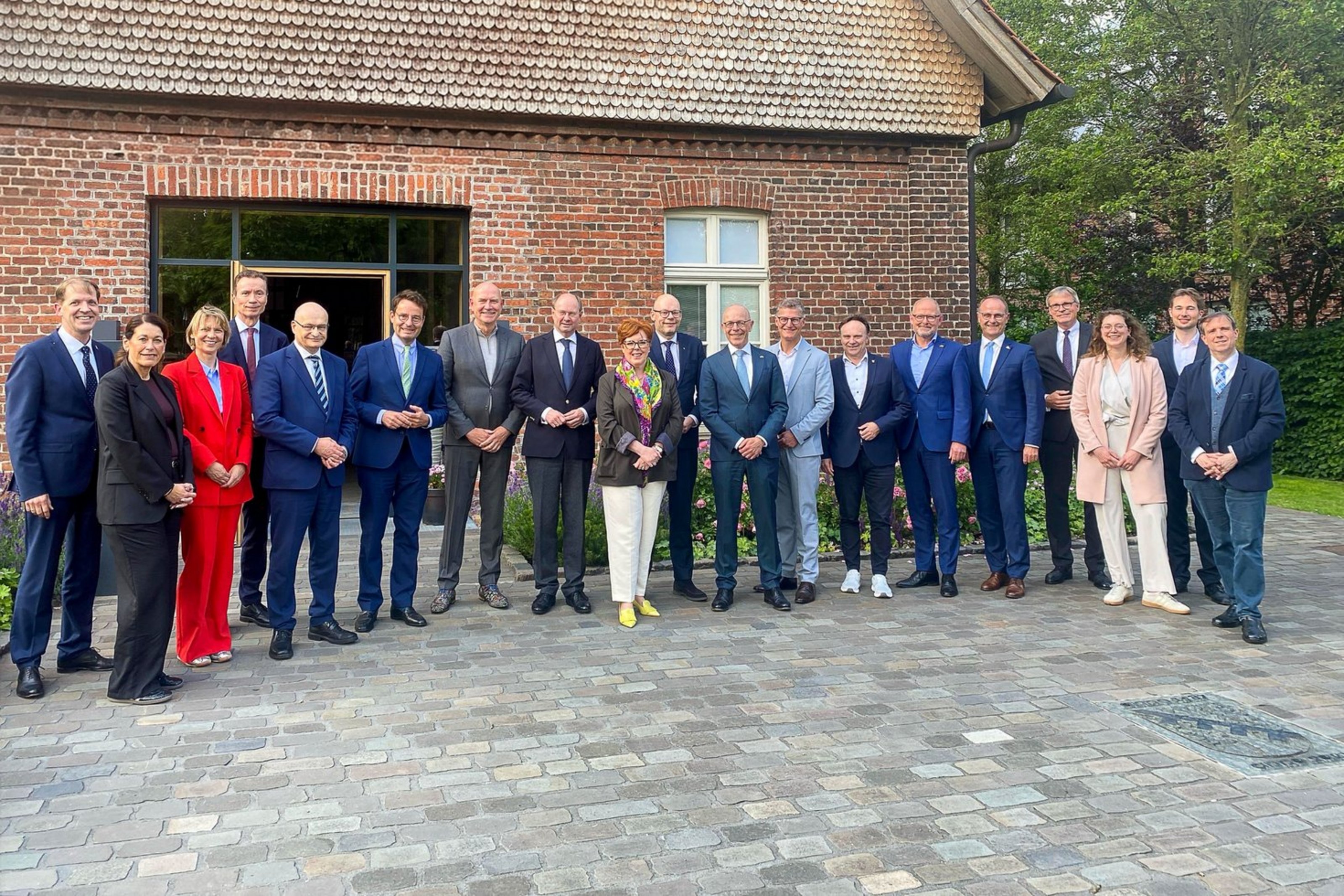 Eine Gruppe von Teilnehmerinnen und Teilnehmern der deutsch-niederländischen Landrätekonferenz steht für ein gemeinsames Foto vor einem Backsteingebäude in Senden.