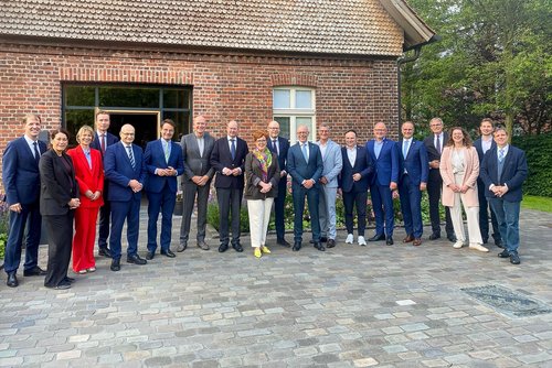 Eine Gruppe von Teilnehmerinnen und Teilnehmern der deutsch-niederländischen Landrätekonferenz steht für ein gemeinsames Foto vor einem Backsteingebäude in Senden.