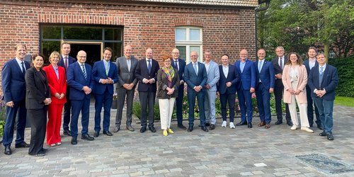 Eine Gruppe von Teilnehmerinnen und Teilnehmern der deutsch-niederländischen Landrätekonferenz steht für ein gemeinsames Foto vor einem Backsteingebäude in Senden.