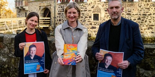 Mehrere Personen stehen vor der Burg Vischering und werben für die Lesung.