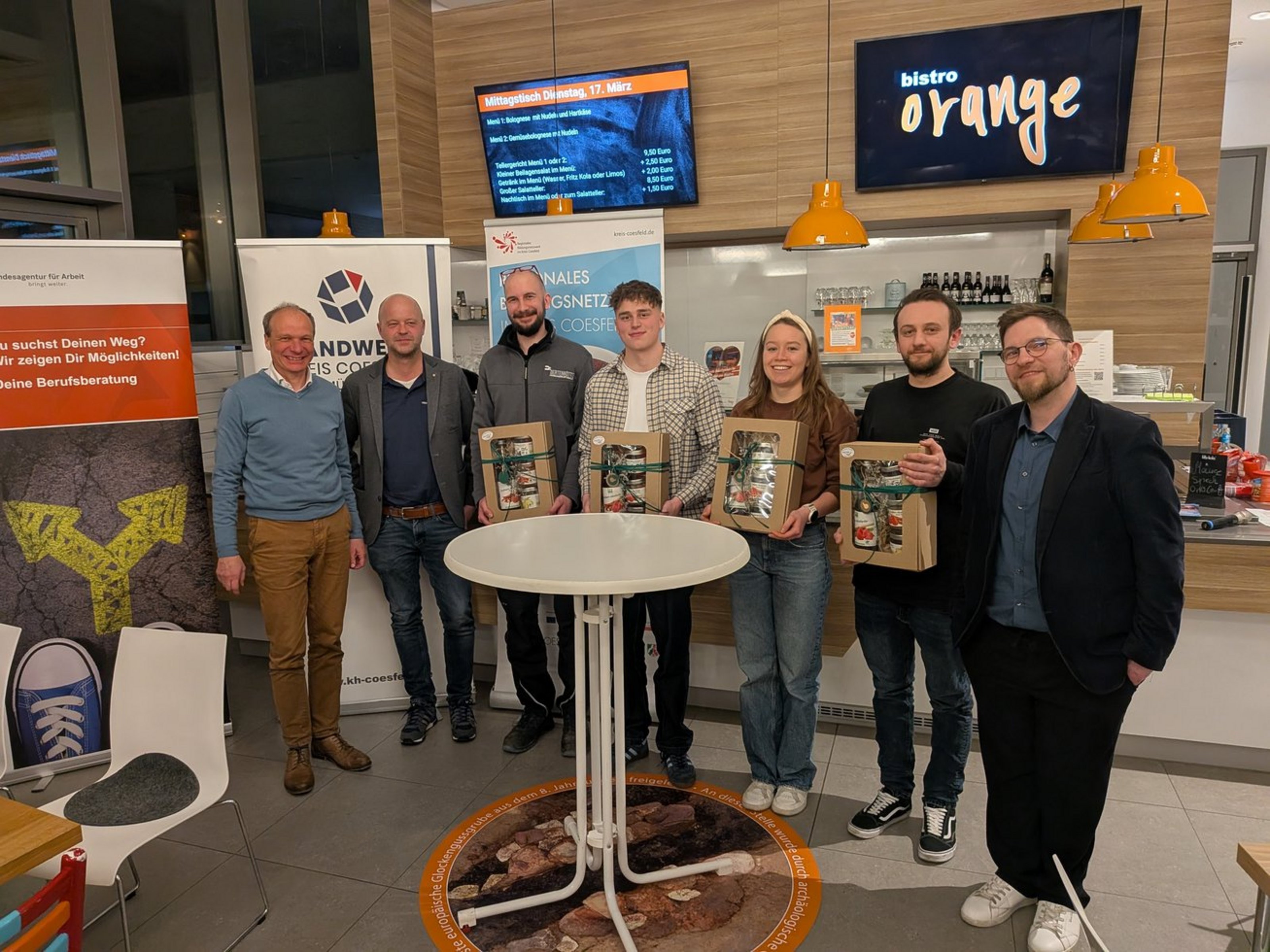 Gruppe von Teilnehmenden und Organisatoren steht im Bistro Orange in Dülmen beim Info-Abend zur beruflichen Orientierung.