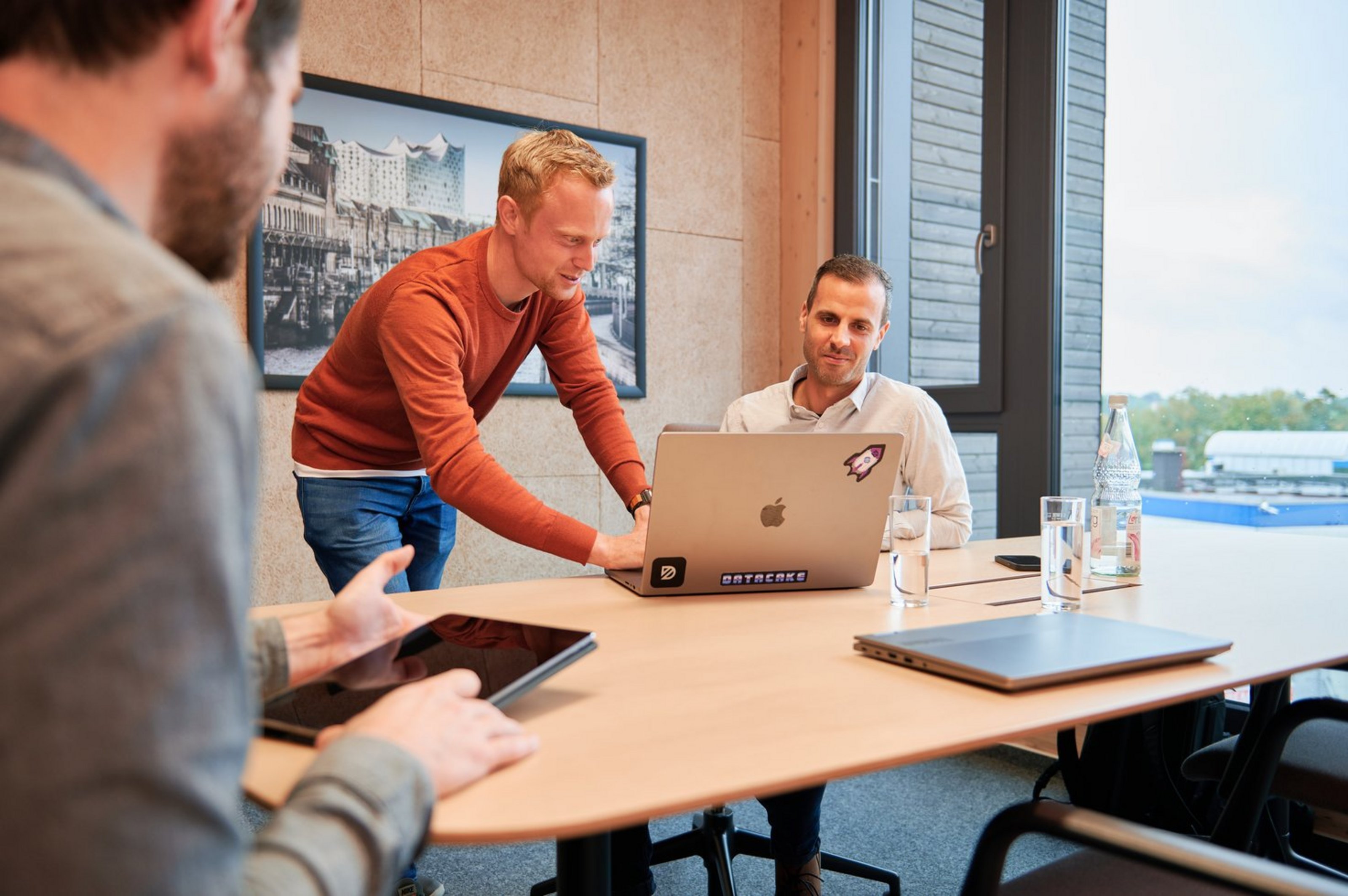 „Gemeinsames Arbeiten in einem Coworking-Space im ländlichen Raum – drei Personen besprechen digitale Inhalte an einem Laptop.“