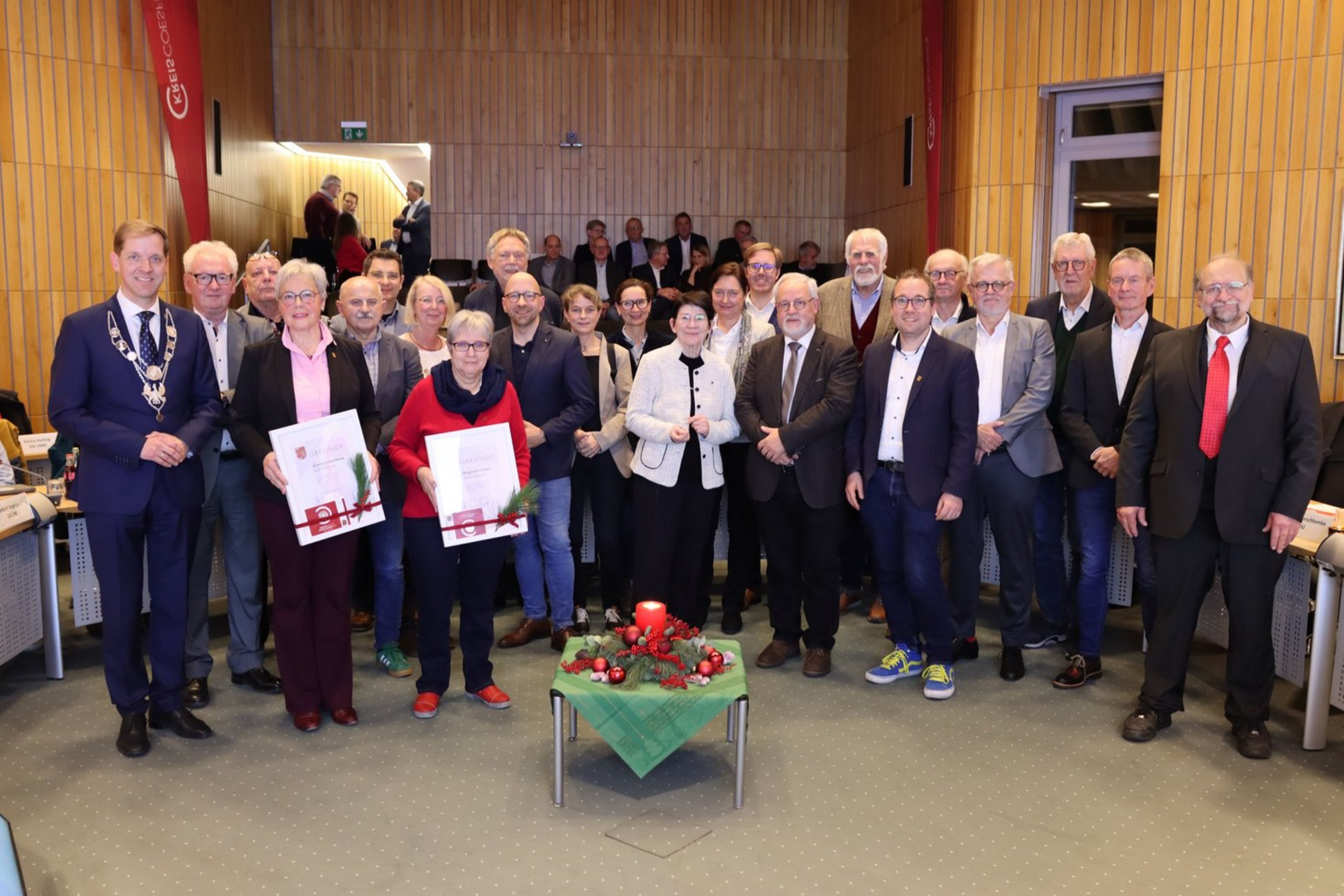 Im Sitzungsaal in Coesfeld steht eine Gruppe von Menshcen vor einem Weihnachtsgesteck.