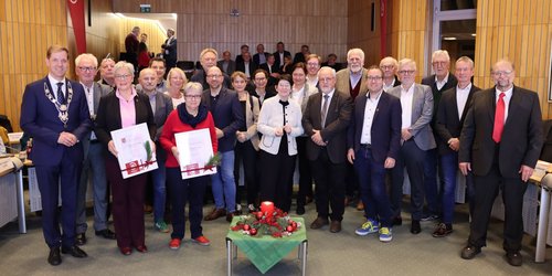 Im Sitzungsaal in Coesfeld steht eine Gruppe von Menshcen vor einem Weihnachtsgesteck.