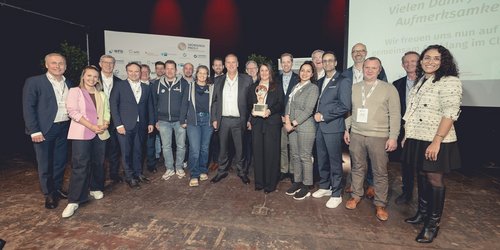 Gruppenfoto auf einer Bühne: ausgezeichnete Gründerinnen und Gründer mit Laudatoren, Partnern und Gästen bei einer Preisverleihung.