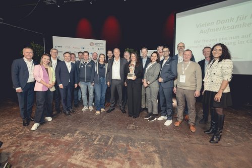 Gruppenfoto auf einer Bühne: ausgezeichnete Gründerinnen und Gründer mit Laudatoren, Partnern und Gästen bei einer Preisverleihung.