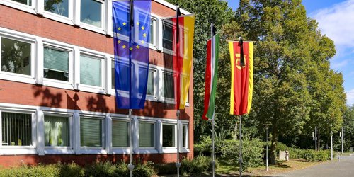 Man sieht vier verschiedene Flaggen, die mit schwarzen Trauerwimpeln versehen sind. Es handelt sich um die Europafahne, die Deutschlandflagge, die Flagge von Nordrhein-Westfalen und vom Kreis Coesfeld.