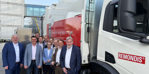 Zehn Personen stehen neben einem großen LKW mit der Aufschrift "REmondis. Wir lassen uns von der Natur antrieben."