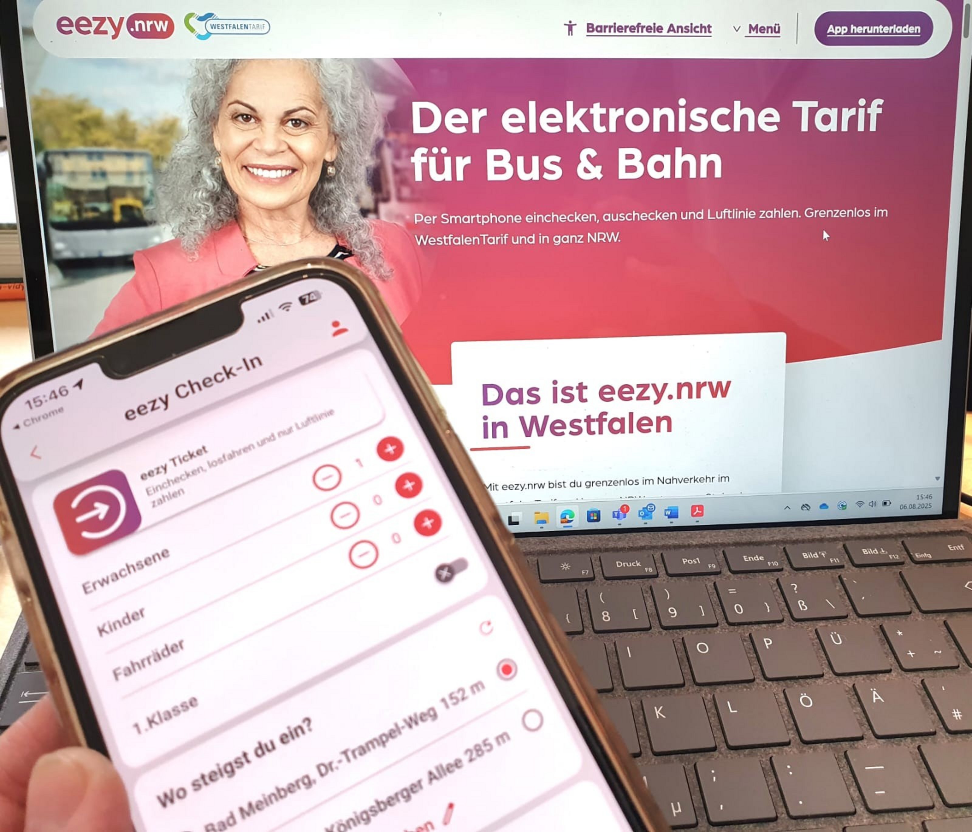 Ein Smartphone wird vor einem geöffneten Laptop gehalten. Auf dem Smartphone ist die App ‚eezy Check-In‘ zu sehen, mit der Fahrgäste für Bus und Bahn einchecken können. Im Hintergrund zeigt der Laptop die Website von eezy.nrw mit der Überschrift ‚Der elektronische Tarif für Bus & Bahn‘. Daneben ist das Foto einer lächelnden älteren Frau abgebildet.
