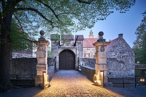 Man sieht die Brücke zu einem Burgtor in der Dämmerung.
