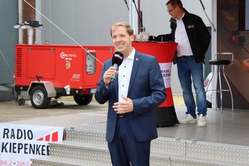 Landrat Dr. Christian Schulze Pellengahr steht vor einer Bühne und hält ein Mirkofon in der Hand. 