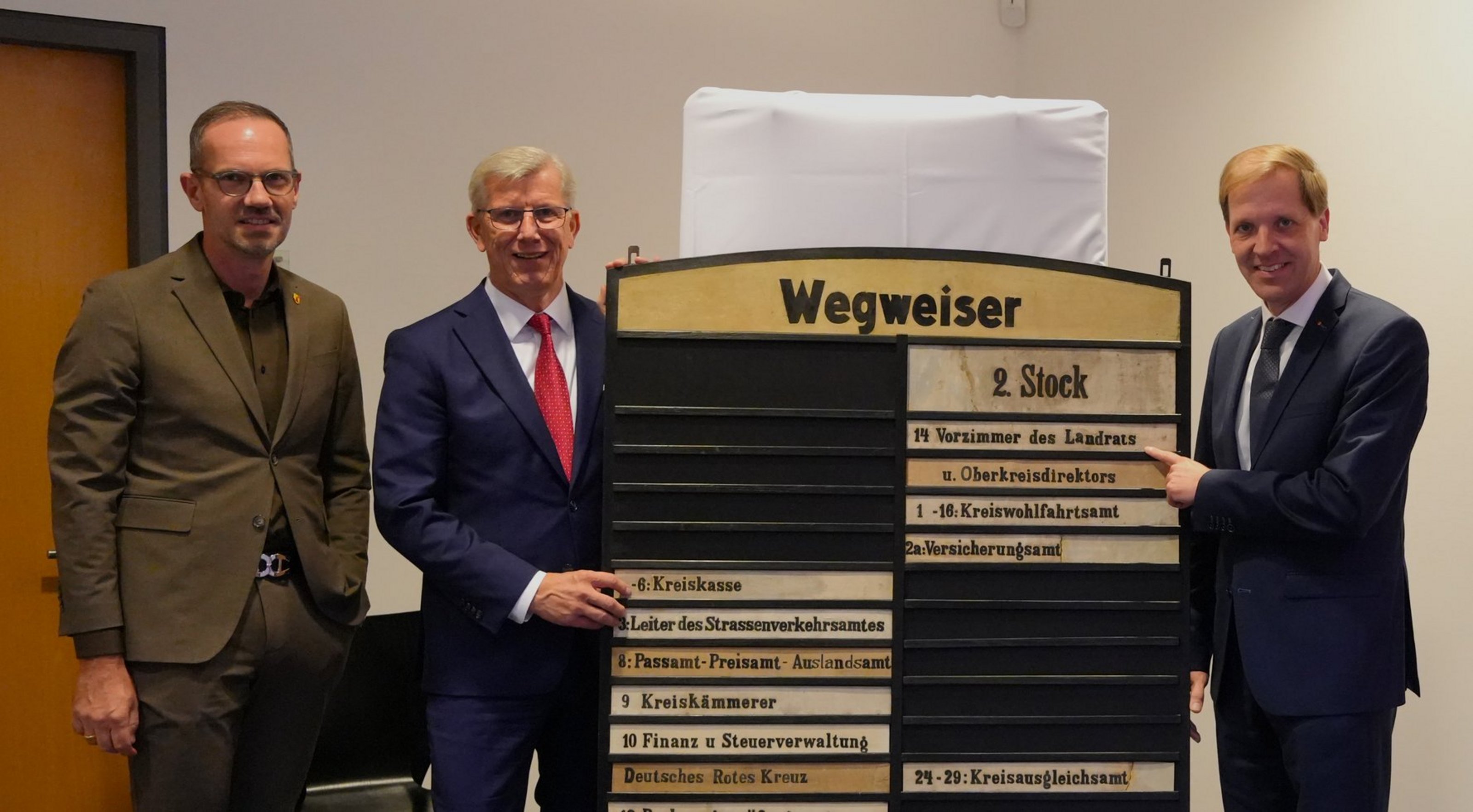 Landrat Dr. Christian Schulze Pellengahr, Vorstandvorsitzender der Sparkasse Norbert Hypki und Bürgermeister Ansgar Mertens  vor einem historischen Wegweiser des Alten Landratsamtes.