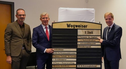 Landrat Dr. Christian Schulze Pellengahr, Sparkassenvorstand Norbert Hypki und Bürgermeister Ansgar Mertens vor einem historischen Wegweiser durch das Alte Landratsamt.