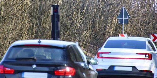 Zwei Autos fahren auf ein Tempomessgerät in Form einer Säule zu.