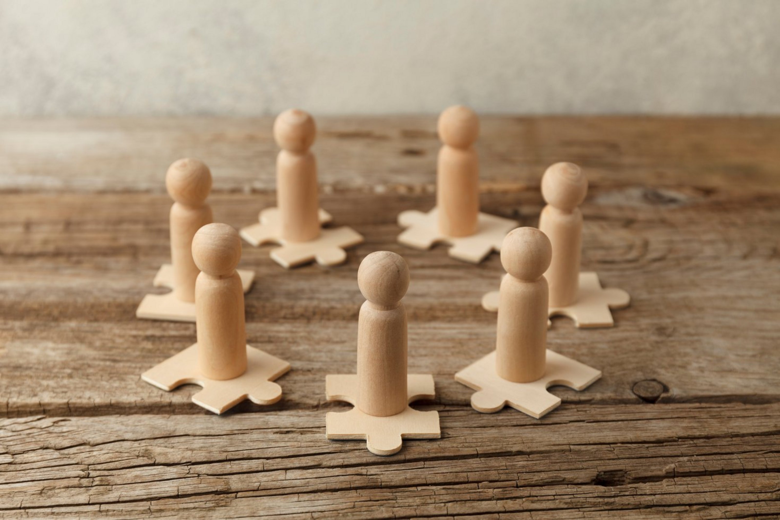 Wooden figures on puzzles. People analytics and optimization, team building. Group connection in business.