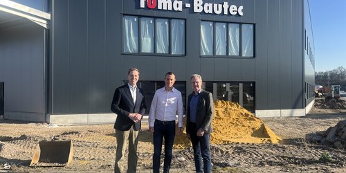 Drei Männer stehen vor dem Firmengebäude von Fuma Bautec und sprechen über die Entwicklung des Unternehmens.