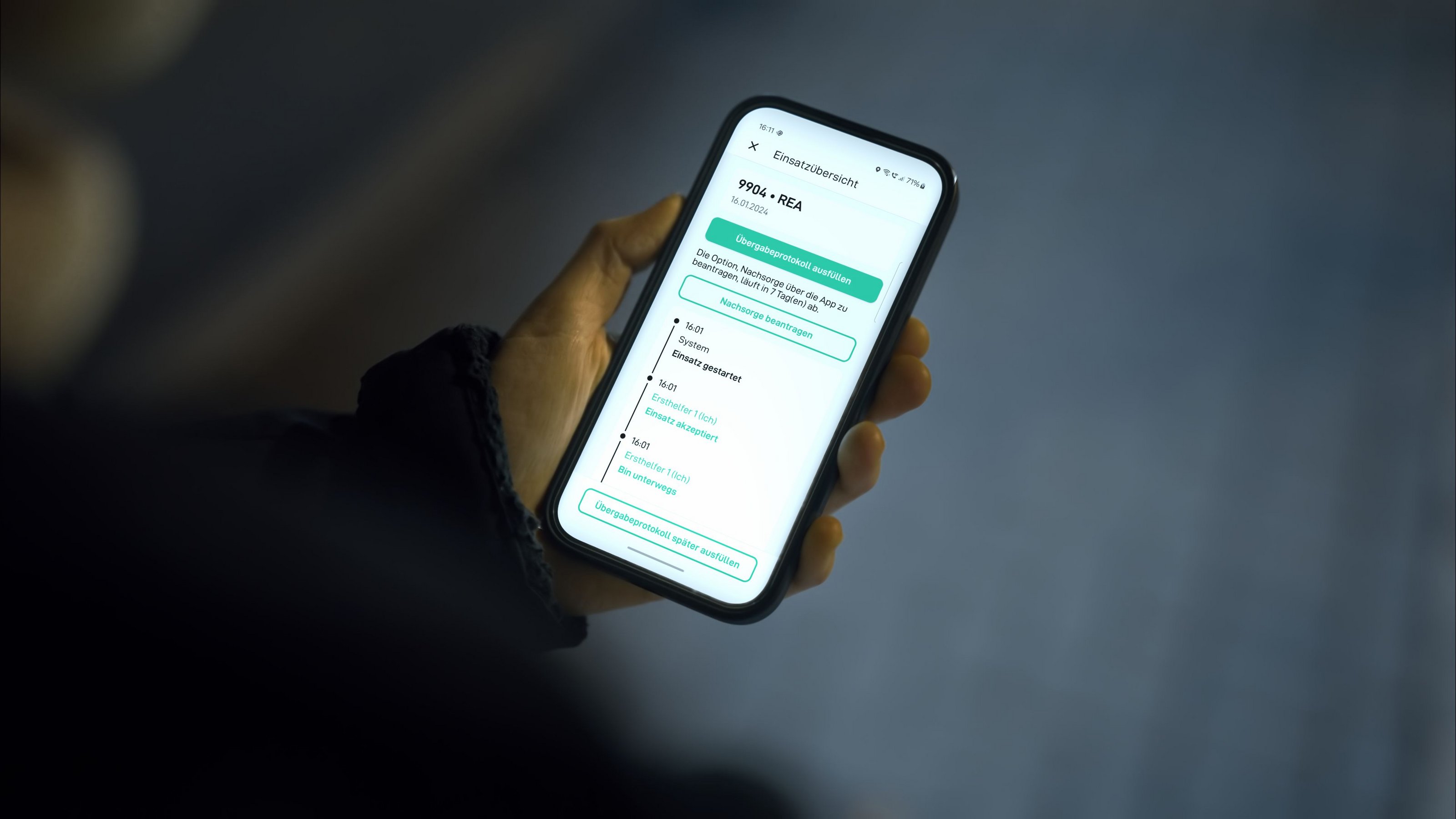 Die Corhelper-App (Foto: umlaut telehealthcare) Eine Hand hält ein Handy. Der Hintergrund ist dunkel. Auf dem Display steht Einsatzübersicht.