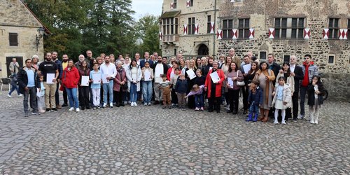 Eine große Gruppe von Menschen steht zur Einbürgerungsfeier vor der Burg Vischering in Lüdinghausen.