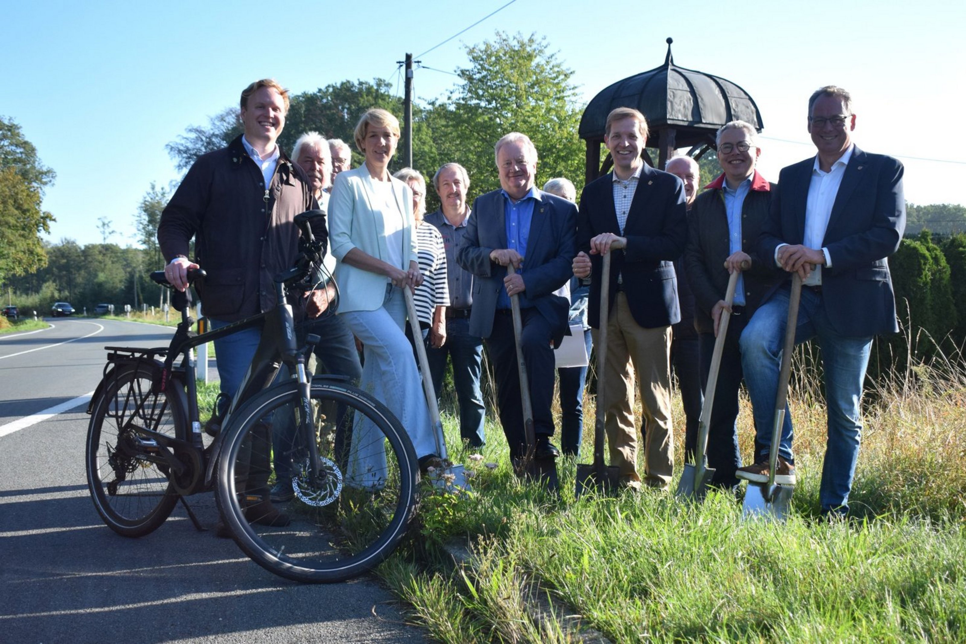 Mehrere Personen setzen beim symbolischen Spatenstich für den neuen Radweg an der Kreisstraße 60 gemeinsam die Spaten an.