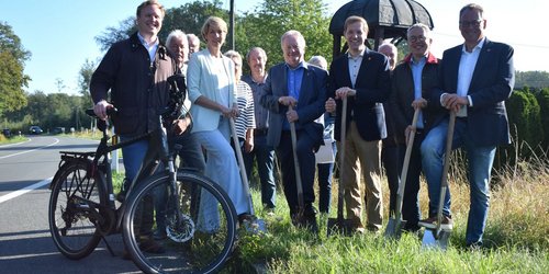 Mehrere Personen setzen beim symbolischen Spatenstich für den neuen Radweg an der Kreisstraße 60 gemeinsam die Spaten an.