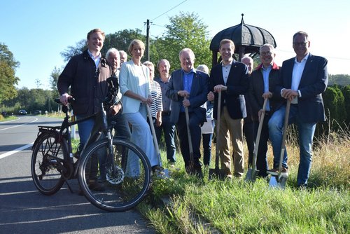 Mehrere Personen setzen beim symbolischen Spatenstich für den neuen Radweg an der Kreisstraße 60 gemeinsam die Spaten an.
