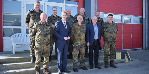 Mehrere Soldaten und Vertreter aus Politik stehen während einer Übung des Kreisverbindungskommandos vor einem Gebäude in Dülmen.