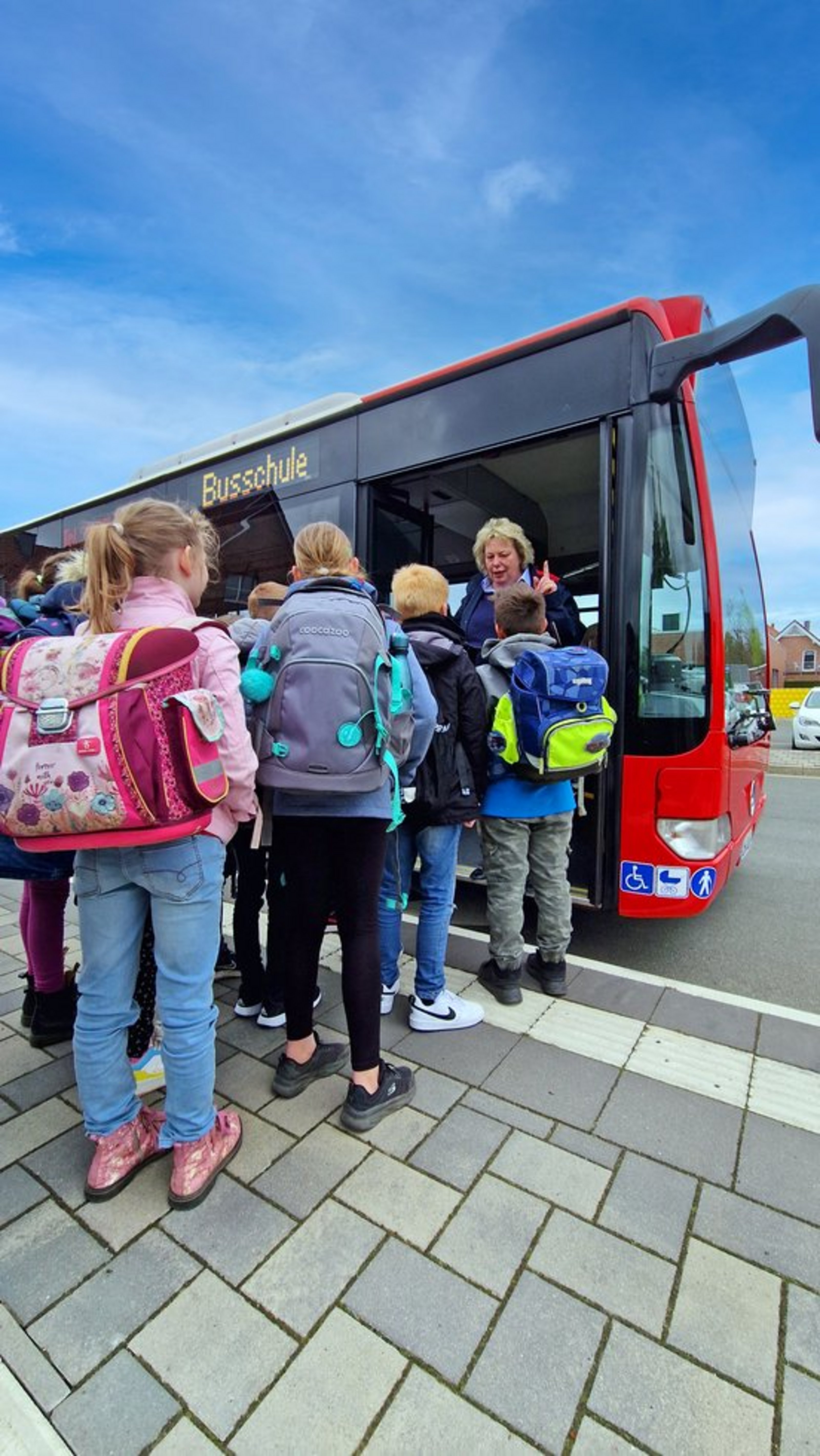 Es wird die Busschule der Regionalverkehr Münsterland (RVM) gezeigt. Zu sehen sind Kinder vor einem RVM-Bus.
