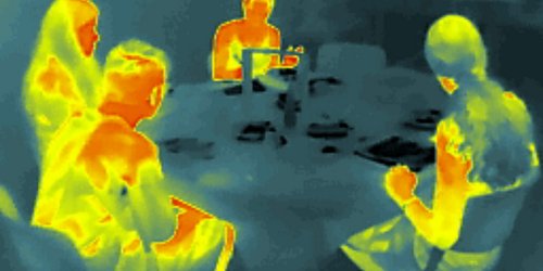 Man sieht die Silhouetten einiger Menschen die an einem Tisch sitzen. Ihre Körper sind in verschiedenen Farbtönen zu sehen, die anzeigen, welche Temperatur diese Körperregion hat.