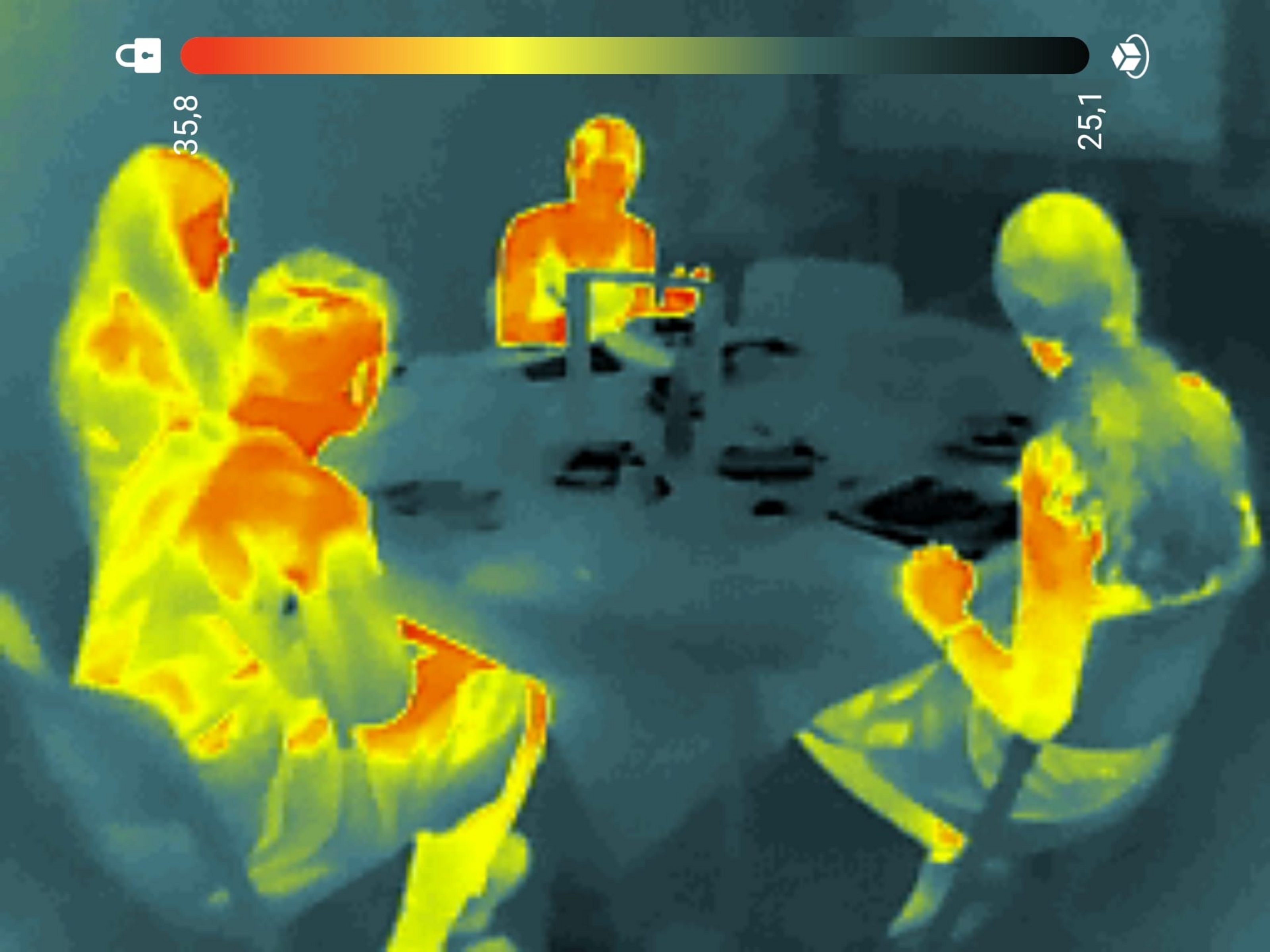 Man sieht die Silhouetten einiger Menschen die an einem Tisch sitzen. Ihre Körper sind in verschiedenen Farbtönen zu sehen, die anzeigen, welche Temperatur diese Körperregion hat.