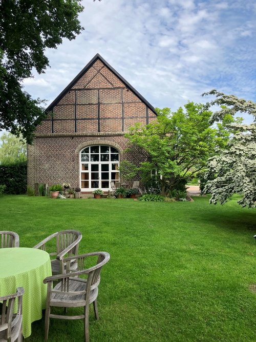 Auf einer grünen Wiese steht ein altes Fachwerkhaus.