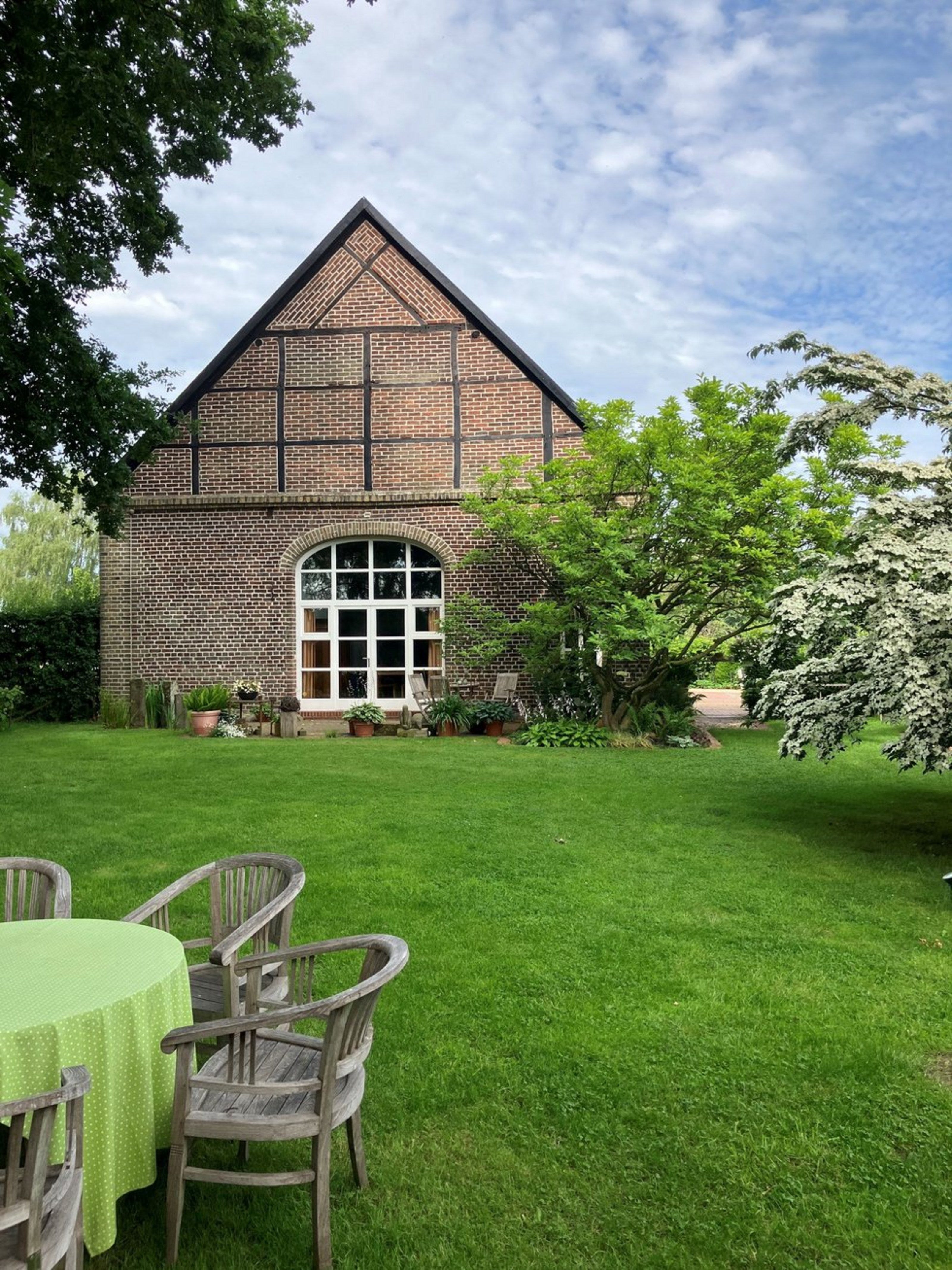 Auf einer grünen Wiese steht ein altes Fachwerkhaus.