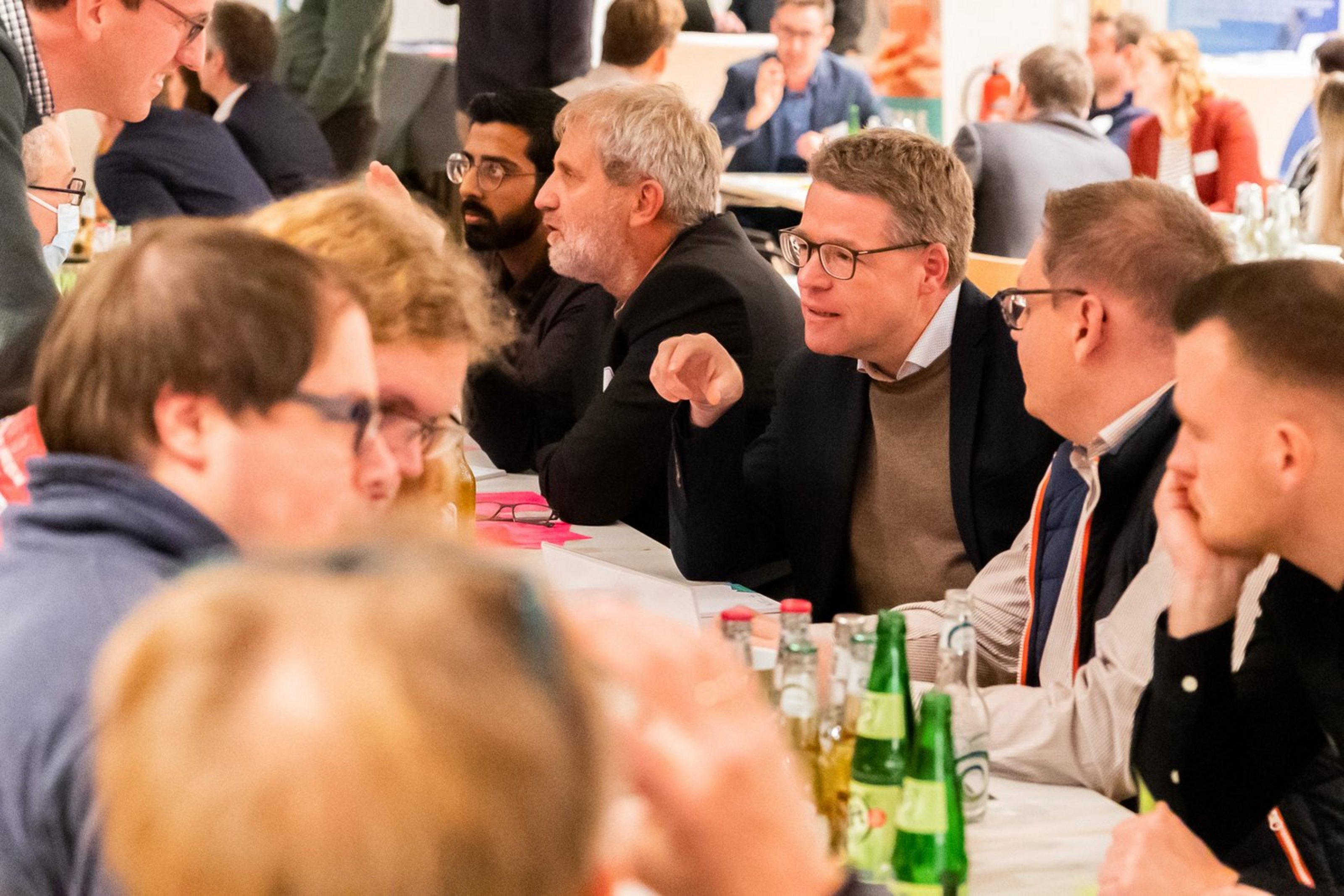 Gruppe von Menschen sitzt an einem langen Tisch und unterhält sich