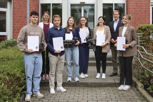 Gruppe von Auszubildenden mit Urkunden und Geschenken vor dem Kreishaus, gemeinsam mit Landrat und Ausbildungsleiterin.