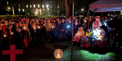 Viele Menschen stehen im dunkeln auf der Wiese vor der Burgkappelle und feiern Gottestdienst.