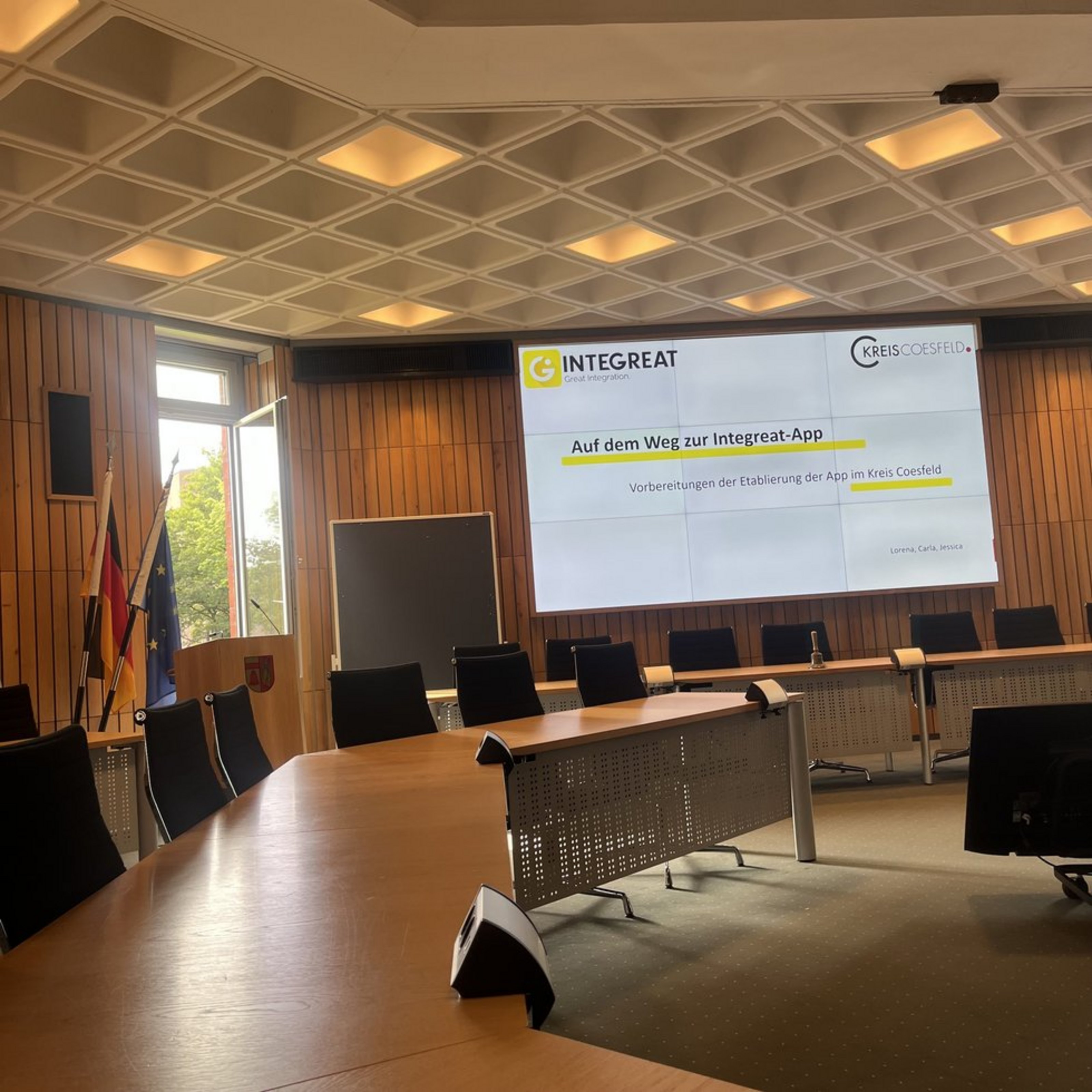 Auf einer Bildschirmpräsentation in einem Sitzungssaal steht "Auf dem Weg zur Integrat-App. Vorbereitung der Etablierung der App im Kreis Coesfeld".