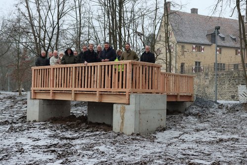 Eine Gruppe von Menschen auf einem Aussichtssteg vot einer Burg.