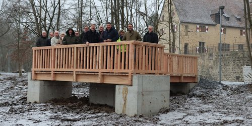 Eine Gruppe von Menschen auf einem Aussichtssteg vot einer Burg.