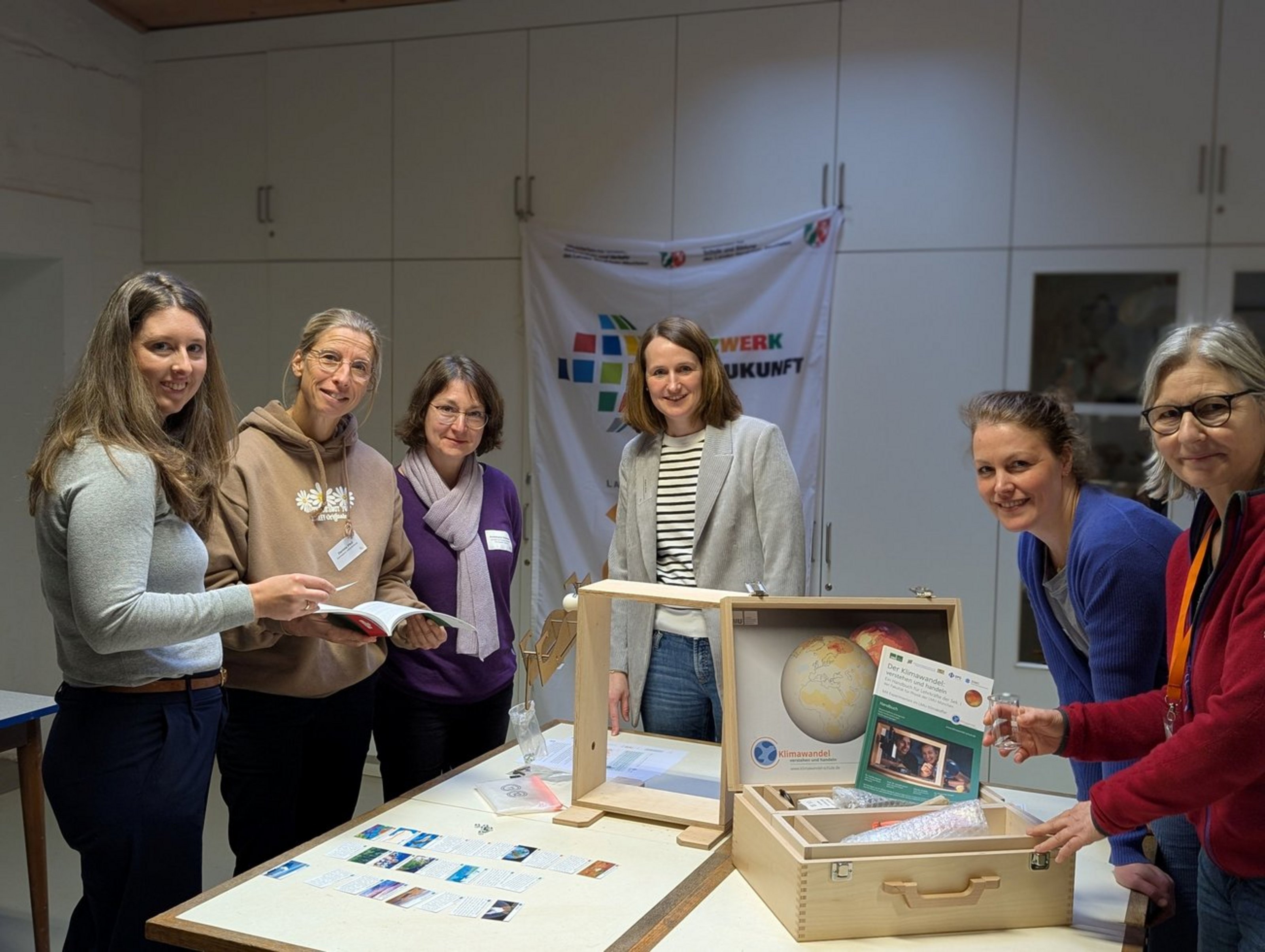 Mehrere Personen stehen an einem Tisch mit dem geöffneten LMU-Klimakoffer und Materialien zum Thema Klimawandel.