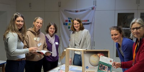 Mehrere Personen stehen an einem Tisch mit dem geöffneten LMU-Klimakoffer und Materialien zum Thema Klimawandel.