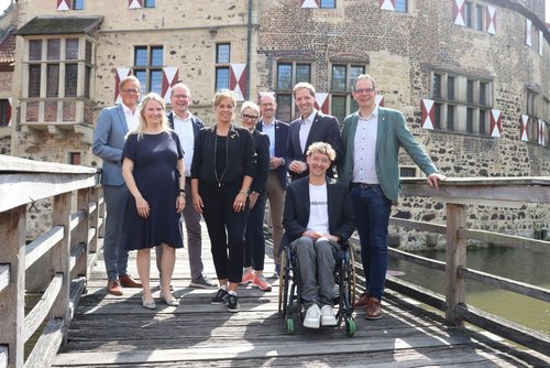 Gruppenfoto mit Ministerin Mona Neubaur und regionalen Vertreterinnen und Vertretern vor der historischen Kulisse der Burg Vischering.