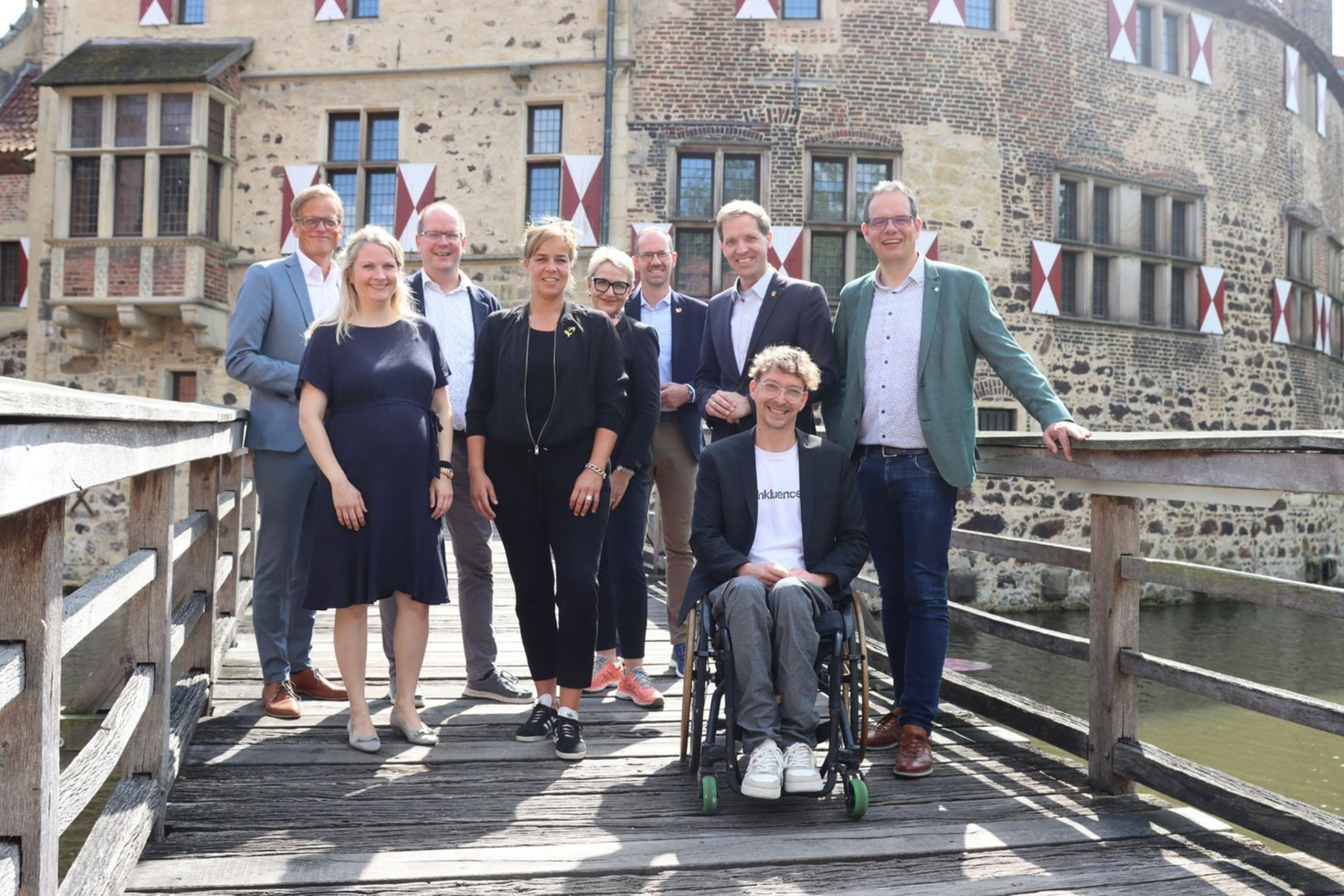 Gruppenfoto mit Ministerin Mona Neubaur und regionalen Vertreterinnen und Vertretern vor der historischen Kulisse der Burg Vischering.