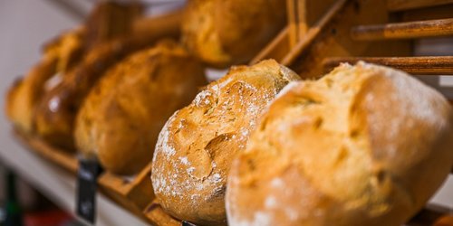 Brötchen liegen in einem schrägen Regal. Zwei kleine Schilder befinden sich an der Kante des Regals.