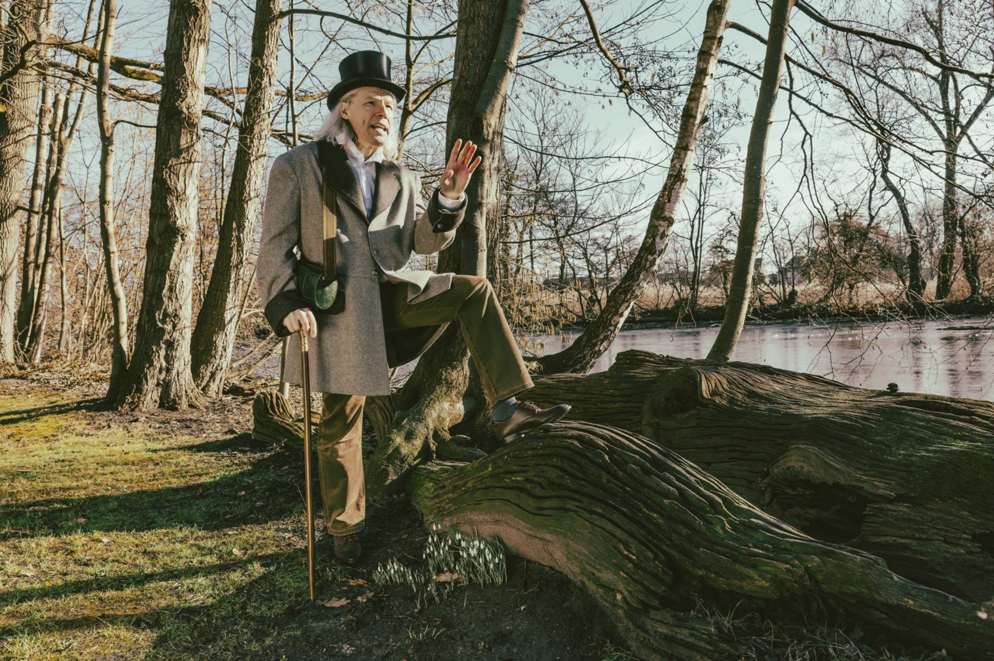 Mit Begeisterung und viel Wissensdurst vermittelt Botaniker Wernekinck in der Schauspielführung „Herbationes 1818“ Einblicke in die faszinierende Pflanzenwelt des Münsterlandes (Foto: Kreis Coesfeld, Andreas Lechtape). Ein Mann in historischem Kostüm mit Zylinder und Gehstock steht an einem See, einen Fuß auf einen liegenden Baumstamm gestellt.