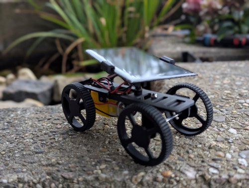 Eine selbstgebautes Miniatur-Auto mit Solarzelle steht auf einem Pflasterstein.