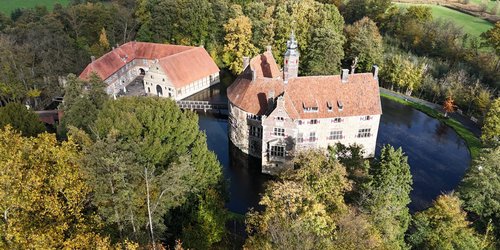 Eine Wasserburg inmitten von Bäumen.