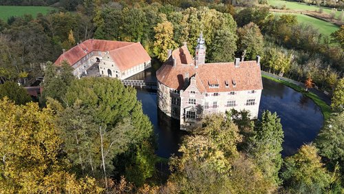 Eine Wasserburg inmitten von Bäumen.