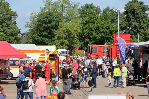 Auf einem Platz sind Einsatzfahrzeuge vom DRK und THW  sowie Rettungswagen ausgestellt. Viele Menschen laufen dazwischen herum oder stehen in Gruppen zusammen.