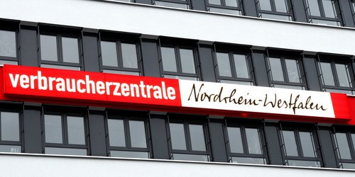 Eine Gebäudefassade mit vielen Fenstern und dem Schriftzug "Verbraucherzentrale Nordrhein-Westfalen" ist zu sehen.